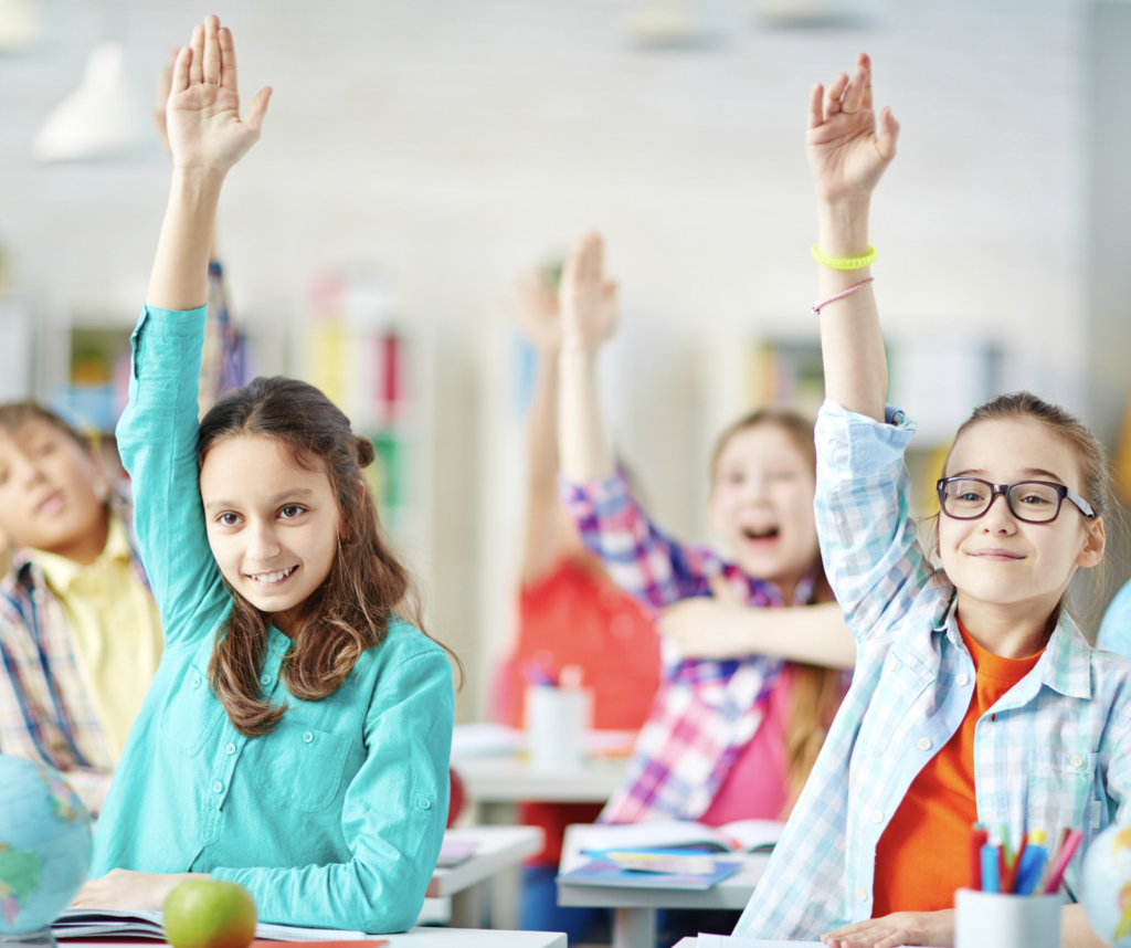 Des élèves dans une classe qui lèvent la main à l'unissons.